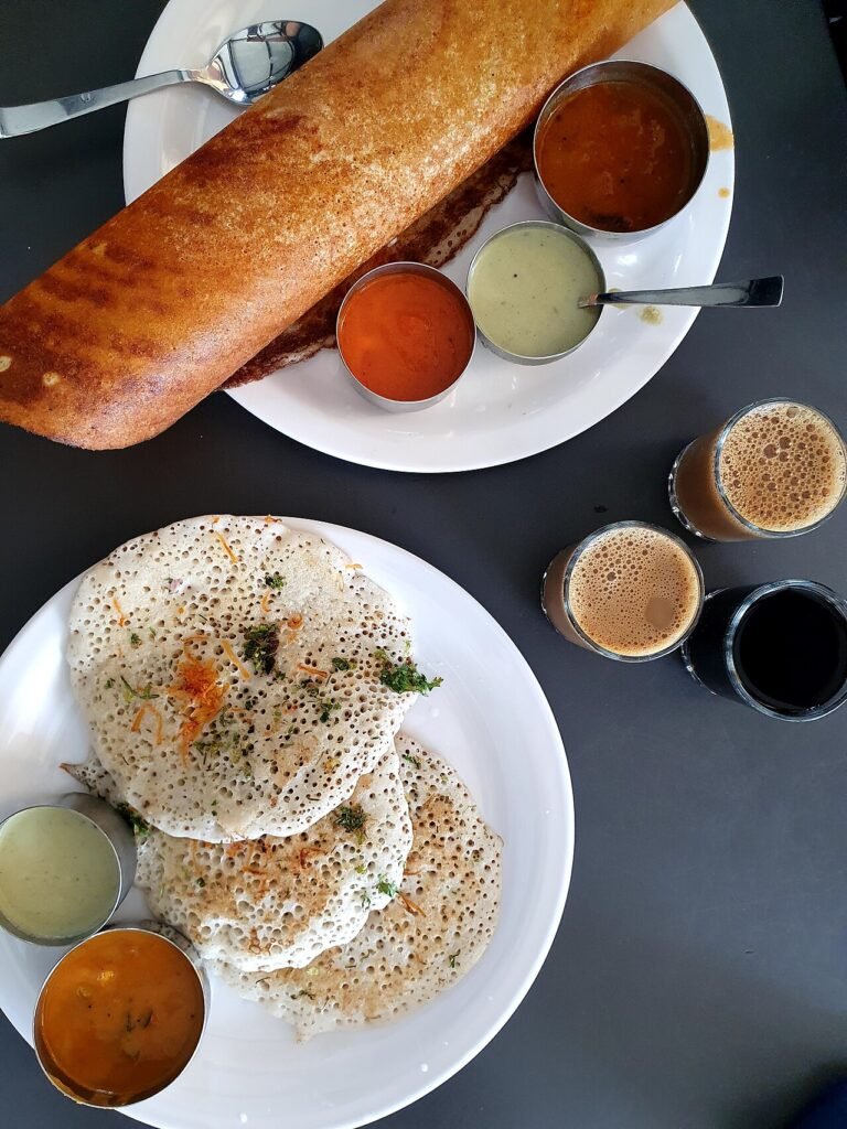 Two types of dosa served with chutney and coffee.